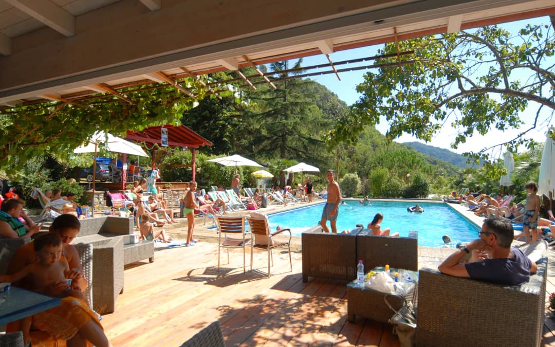 Overdekt houten terras met loungebanken en uitzicht op het zwembad van Camping Delle Rose