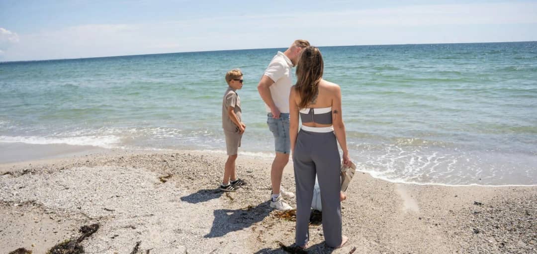 Gezin aan de waterlijn op een strand met schelpen en kiezels aan de Bretonse kust