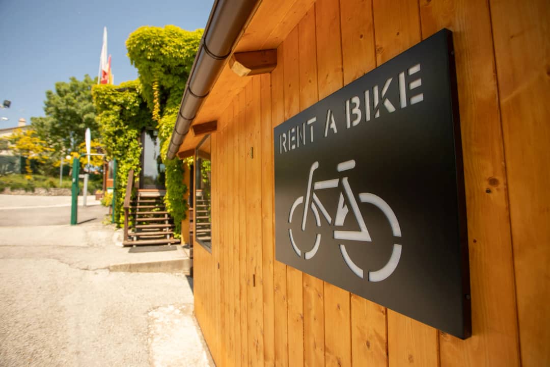 Bord met de tekst Rent a bike en een fietssilhouet op de houten gevel van de fietsverhuur bij Centro Vacanze San Marino