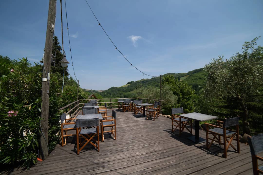 Houten terras met regisseursstoelen, lichtsnoeren en uitzicht over de groene heuvels van Le Marche